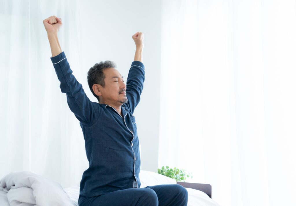朝、起床し伸びをしている男性