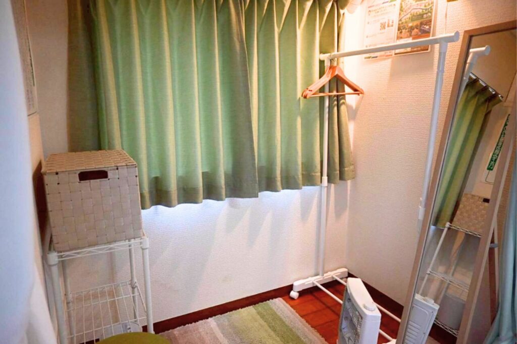 更衣室の様子です。お洋服をかけるハンガーラックやカゴ、キャスターがあり、鏡と椅子があるお部屋です。カーテンで仕切られています。