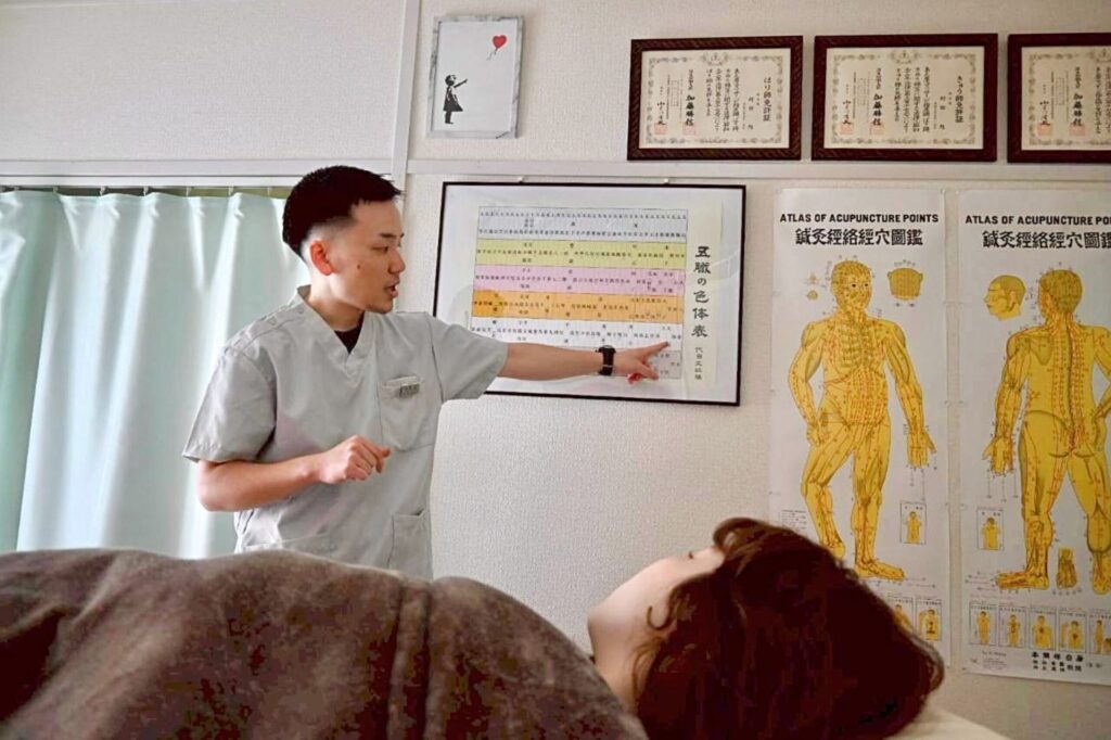 ベッドに横になっている患者様に五行論について説明している様子