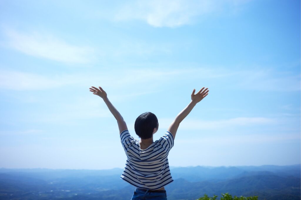 空へ両手を伸ばしている女性